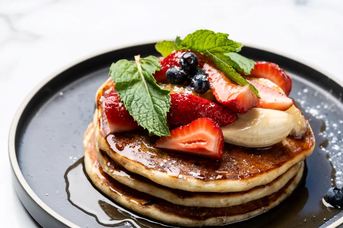 Pancakes stacked with strawberries, blueberries and banana