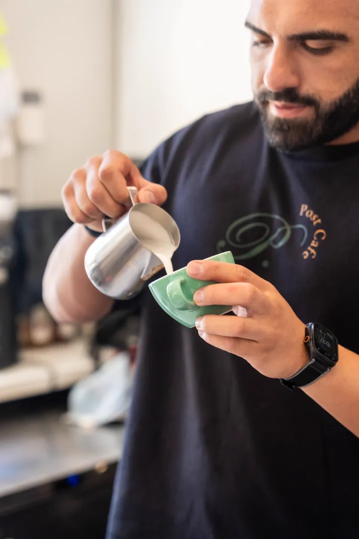 Barista pouring milk into a coffee